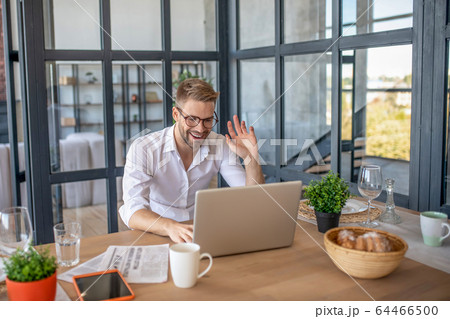 Young handsome man in white shirt greeting his colleague online 64466500