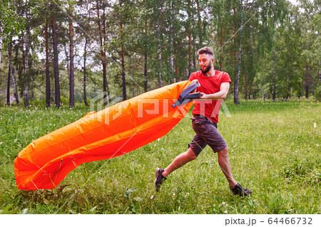 A young man inflates a lamzac with air. A man inflates an air sofa. on the background of the forest 64466732