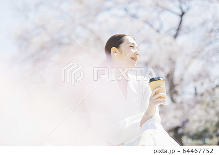 花見をしながら公園でコーヒーを飲むミドル女性の写真素材