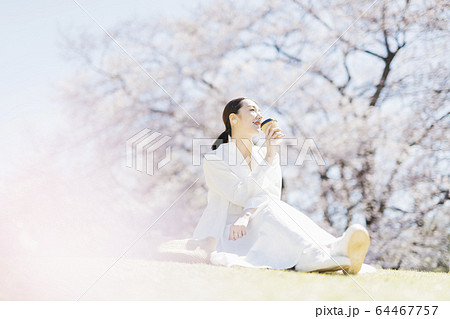 花見をしながら公園でコーヒーを飲むミドル女性の写真素材