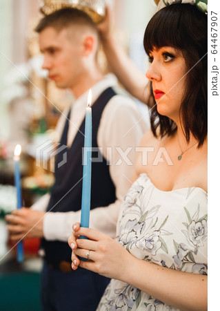 Bride and groom holding candles in church 64467907
