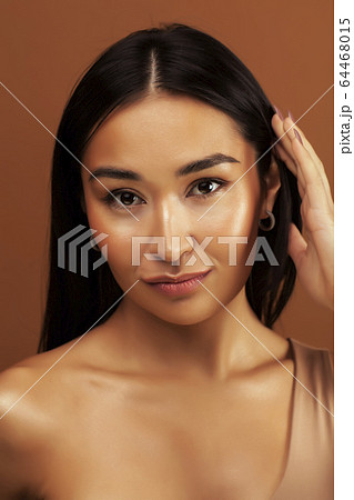 young pretty asian woman cheerful smiling posing on warm brown background, lifestyle people concept 64468015