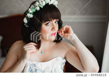 Luxury bride in white dress posing while preparing for the wedding ceremony 64468019