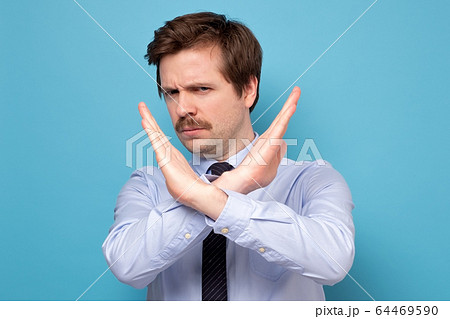 Serious young man in shirt showing stop sign Serious young man in shirt showing stop sign 64469590