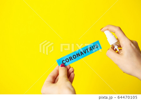Woman uses hand antiseptic on yellow background. 64470105