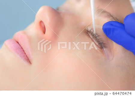 Beautician bending lashes with needle into curlers, lift eyelashes laminaton. 64470474