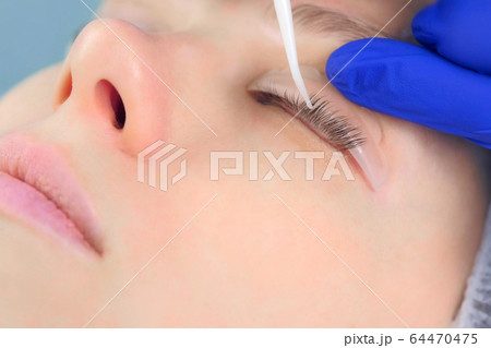 Cosmetologist bending lashes with needle into curlers, lift eyelashes laminaton. 64470475