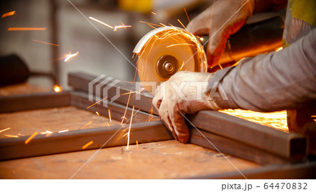 A man worker cutting metal beam in half using grinder machine 64470832