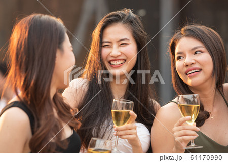 Group of young beautiful happy asian women holding glass of wine chat together at party Group of young beautiful happy asian women holding glass of wine chat together at party 64470990