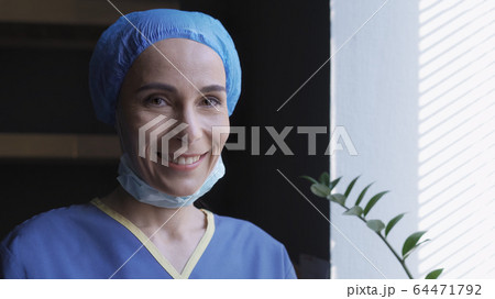 Smiling Female Doctor Rejoices Standing Near Window 64471792