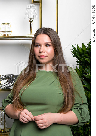 Studio shot of voluptuous woman posing in green dress over white background 64474009