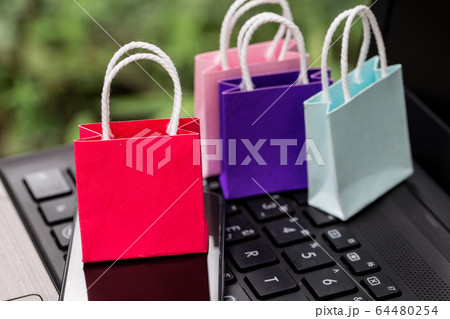 Colorful paper shopping bags with mobile phone on a laptop keyboard. Concept about online shopping that customers can buy everything from home or office. Via the tool electronics. 64480254