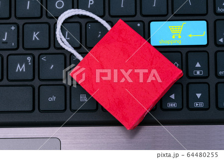 Small red paper shopping bags on laptop keyboard.Wait for the customer to click the button. for shopping at home or office which customers can purchase items or services or goods remotely. 64480255