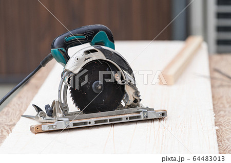 床材を電動丸ノコでカットしている職人の手元クローズアップ 64483013