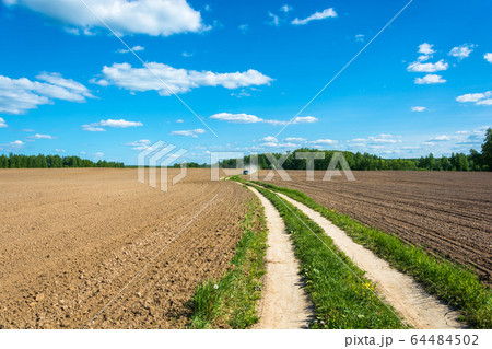 Rural road between two plowed fields. Rural road between two plowed fields. 64484502