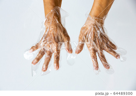 Senior woman's hands wearing disposable protective plastic glove on grey background, Close up shot, Prevention from covid19, Coronavirus, Bacteria, Healthcare 64489300