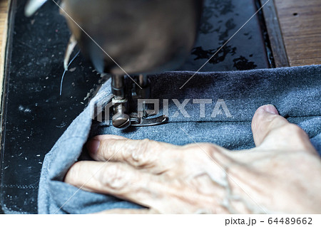Senior woman's stitching grey fabric on vintage sewing machine, Thread, Needle, Close up shot, Selective focus, Sewing process, Female's hobby. Tailor concept Senior woman's stitching grey fabric on vintage sewing machine, Thread, Needle, Close up shot, Selective focus, Sewing process, Female's hobby. Tailor concept 64489662