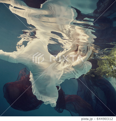 Portrait of a girl floating underwater Portrait of a girl floating underwater 64490312