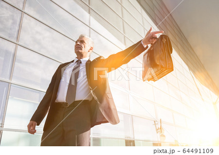 Portrait of mature businessman calling taxi in the 64491109