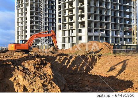 Excavator digs ground at a construction site  64491950