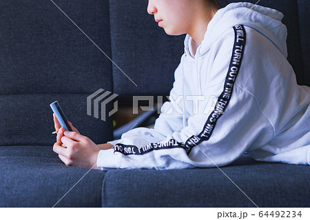 スマホ　SNS　見る　中毒　留守番　コミュニケーション　女性　中学生　高校生　日本人　ソファー　休校 64492234