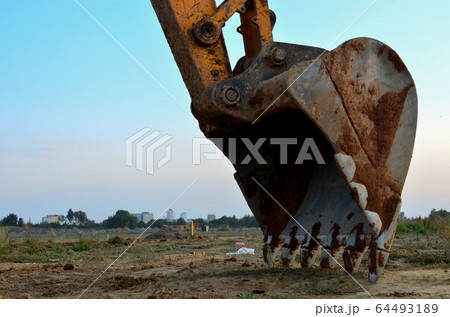 Large metal iron ladle. Excavator bucket for digging a pit and pipeline ditch at a construction site Large metal iron ladle. Excavator bucket for digging a pit and pipeline ditch at a construction site 64493189