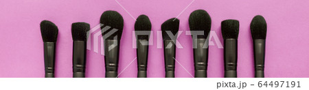 Flat lay of black makeup brushes collection on pink background 64497191