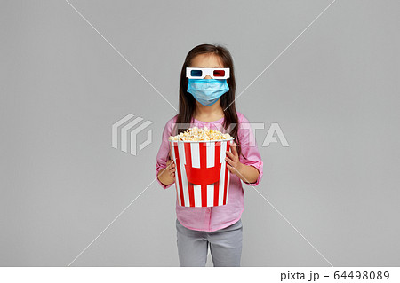 little child girl in mask holding popcorn bucket little child girl in mask holding popcorn bucket 64498089