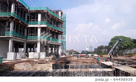 The construction site is operating during the day. Workers are busy carrying out their activities as planned under the supervisor's supervision. 64498939
