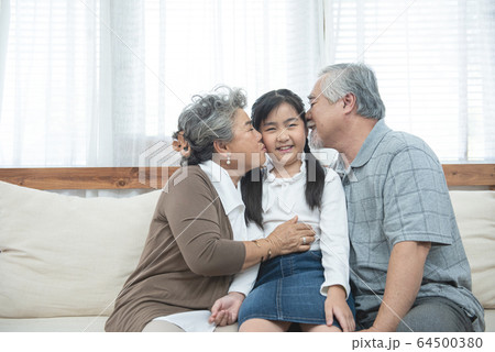 Asian grandparents kiss granddaughter cheek at home Asian grandparents kiss granddaughter cheek at home 64500380
