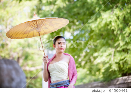 Portrait of an Asian Women in Thai Lanna and Shan Traditional Clothes are Standing and hold umbrella Against Thailand Temple 64500441