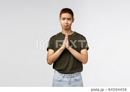Please help me out. Portrait of hopeful clingy cute asian man asking apology, clasp hands together in pray, gloomy looking camera pleading, begging you, standing grey background Please help me out. Portrait of hopeful clingy cute asian man asking apology, clasp hands together in pray, gloomy looking camera pleading, begging you, standing grey background 64504456