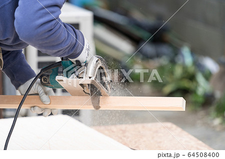 床材を電動丸ノコでカットしている職人の手元クローズアップ 床材を電動丸ノコでカットしている職人の手元クローズアップ 64508400