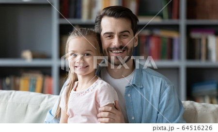Father and daughter sitting on couch smiling looking at camera 64516226