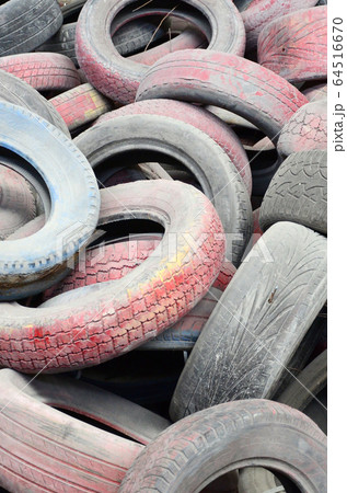 A picture of many old used tires left on a waste A picture of many old used tires left on a waste 64516670