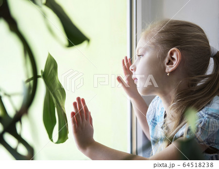Sad child girl by the window Sad child girl by the window 64518238