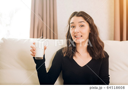 Beautiful young woman with glass of milk at home 64518608