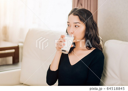Beautiful young woman with glass of milk at home 64518845