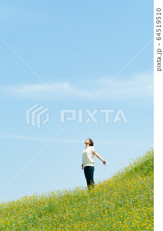 黄色い花咲く草原で深呼吸をする女性 64519510