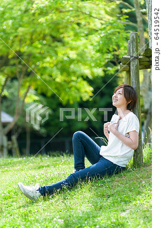 木陰で本を読みながら空を見上げる女性 64519542