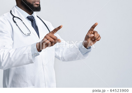 Cropped of black doctor pointing with two fingers Cropped of black doctor pointing with two fingers 64523900