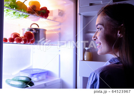 Cheerful housewife choosing vegetables for cooking late dinner Cheerful housewife choosing vegetables for cooking late dinner 64523967