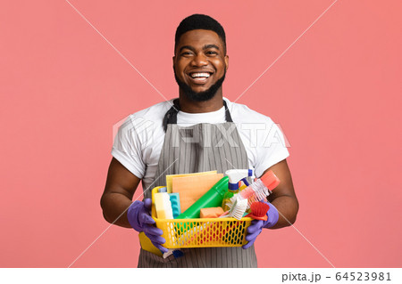 Portrait of positive black man holding basket with cleaning tools Portrait of positive black man holding basket with cleaning tools 64523981