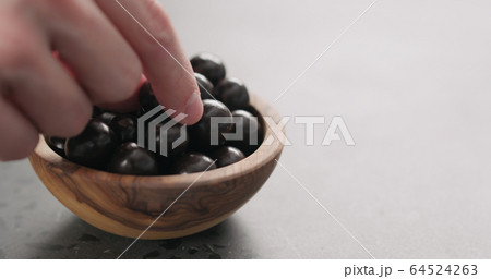 man hand take chocolate covered hazelnuts fall from olive wood bowl with copy space 64524263