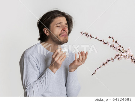 Man smelling flowers and suffer from allergies Man smelling flowers and suffer from allergies 64524695