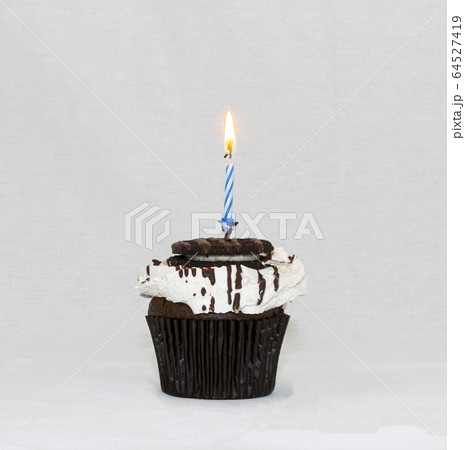 Cookies and cream cupcake with blue candle burning Cookies and cream cupcake with blue candle burning 64527419