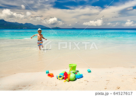 Three year old toddler playing on beach 64527617