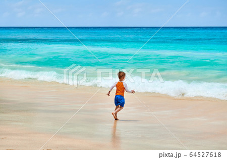 Three year old toddler boy running on beach 64527618