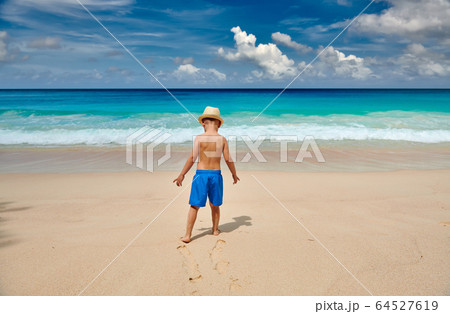 Three year old toddler boy walking on beach 64527619