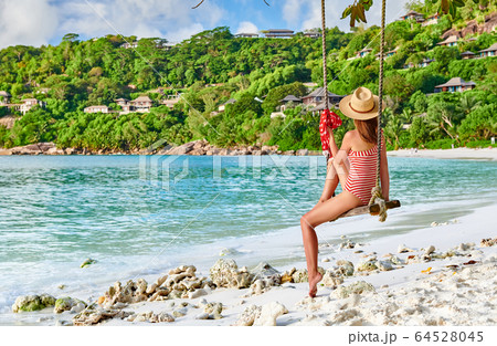 Woman swinging at tropical beach, Seychelles. Woman swinging at tropical beach, Seychelles. 64528045